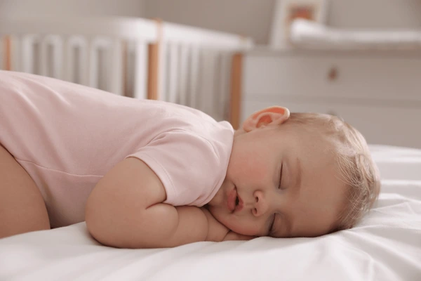 Baby sleeping in Lumolog smart crib with sleep monitor